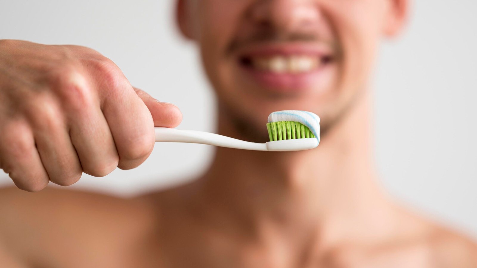 front-view-defocused-man-holding-toothbrush-with-toothpaste-it